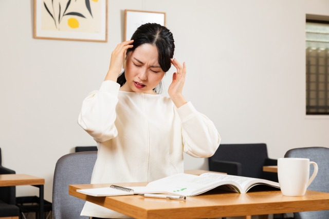 頭痛で頭を抑えている人 頭痛に顔をしかめる